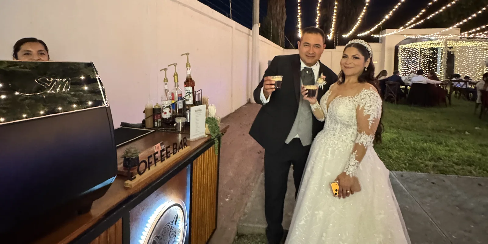 Novios brindando con café Selva Norte junto a la barra iluminada